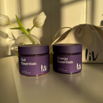 Two purple containers labeled 'Energy Essentials' on a neutral background with a flower.