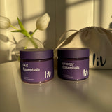Two purple containers labeled 'Energy Essentials' on a neutral background with a flower.