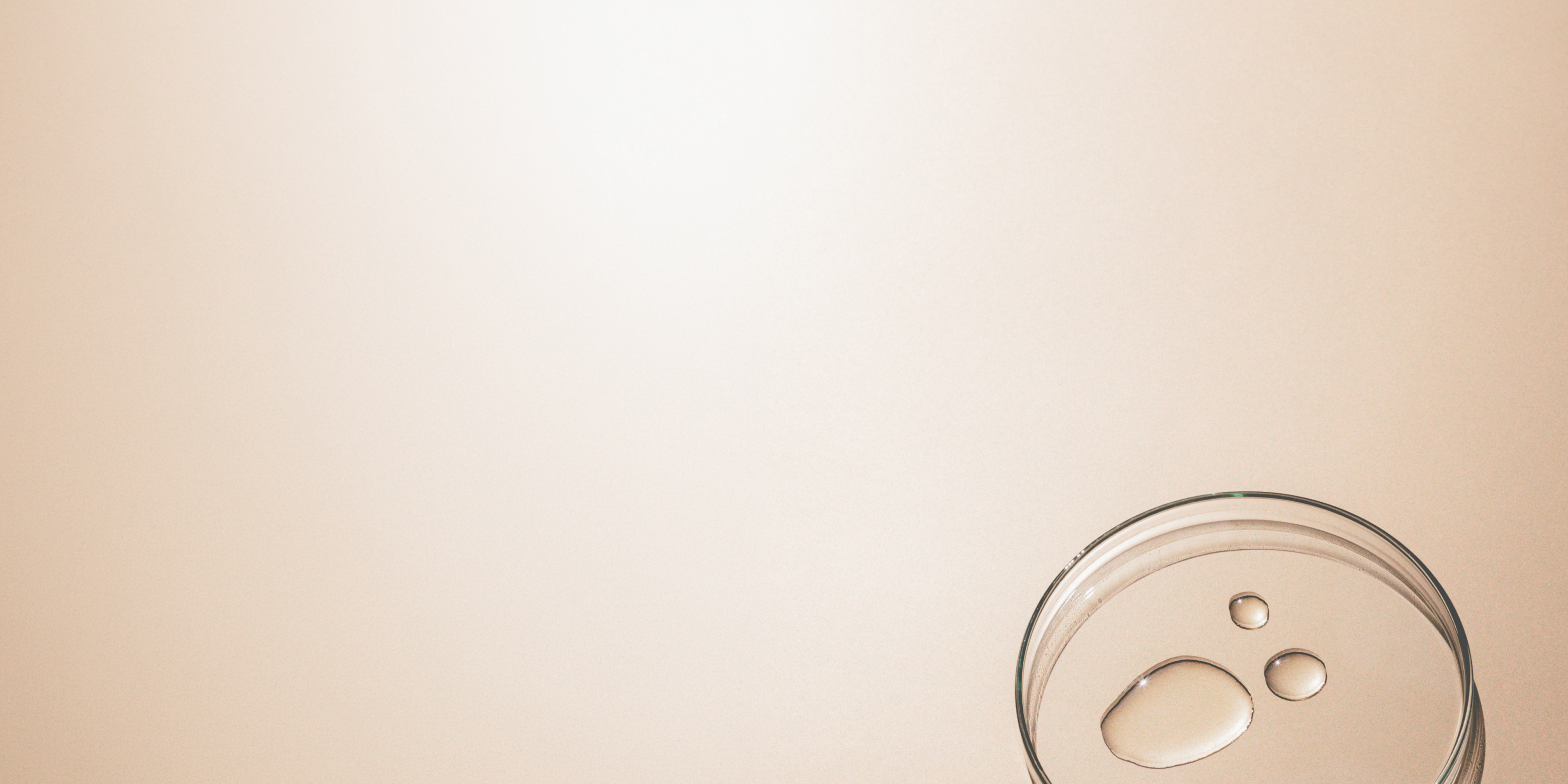 Clear glass with water droplets on a beige background