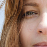 Close-up of a person with light brown hair and green eyes.