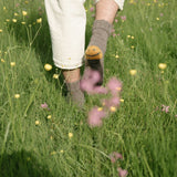 Person wearing white pants and gray socks walking through a field of wildflowers.