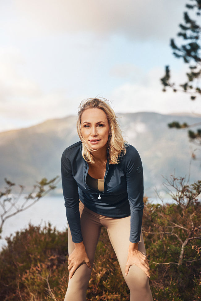 Woman in athletic wear standing outdoors with mountains in the background