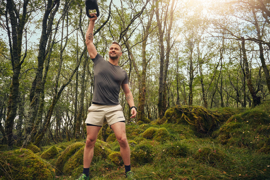 Man exercising with a kettlebell in a forest setting