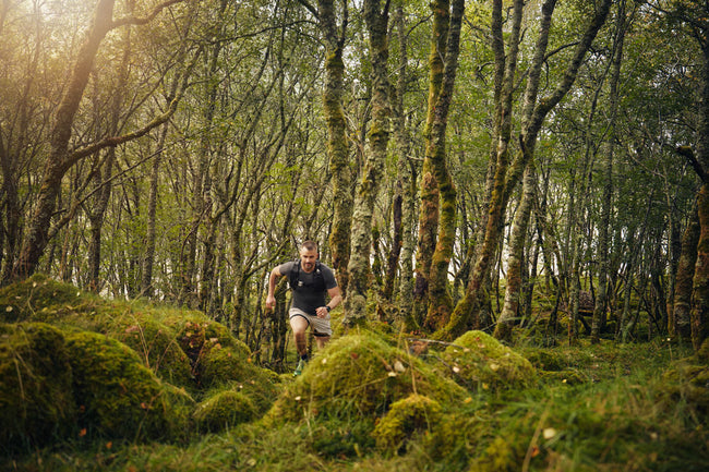Man running through a forest with moss-covered trees