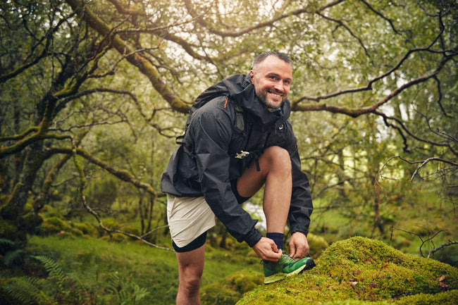 Man tying his shoe in a forest setting
