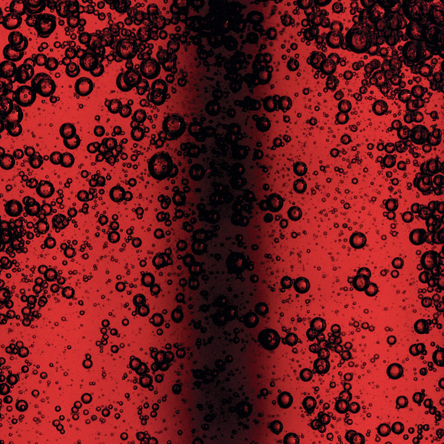 Close-up of red liquid with black bubbles on a red background