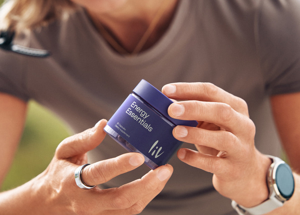 Person holding a blue container labeled 'Energy Essentials' with a blurred outdoor background