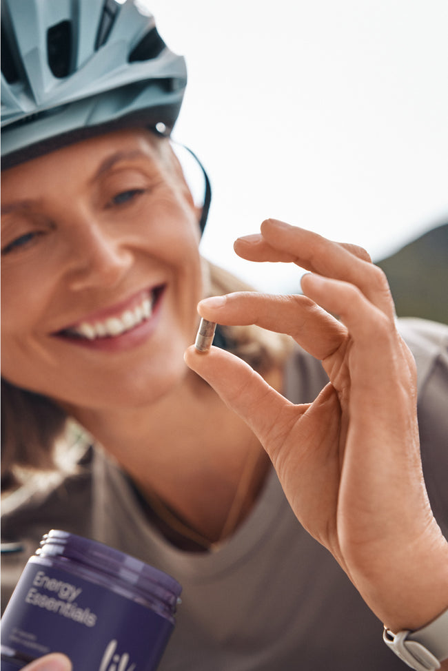 Person holding a supplement capsule with a 'Fuel' container in the background