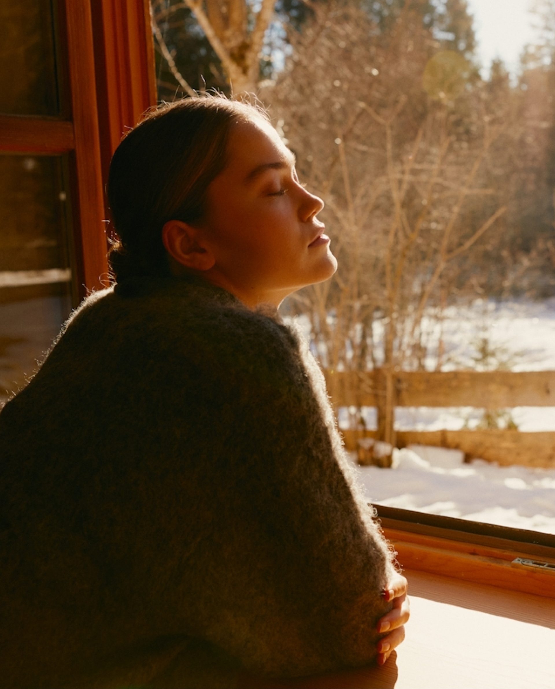 Woman sitting by a window with a snowy landscape outside